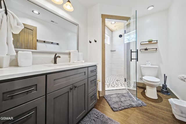 full bathroom featuring visible vents, toilet, wood finished floors, a shower stall, and vanity