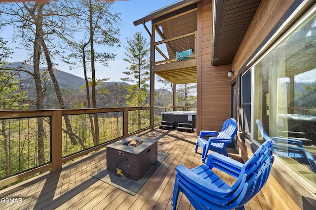 deck featuring a mountain view, a view of trees, and a fire pit