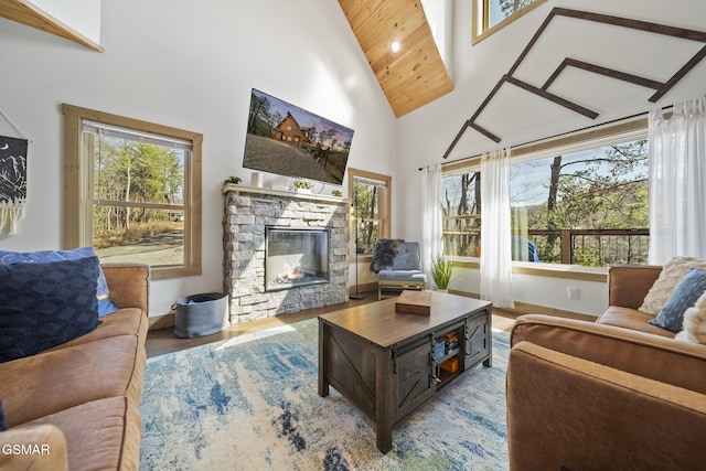 living area featuring a wealth of natural light, a stone fireplace, high vaulted ceiling, and wood finished floors