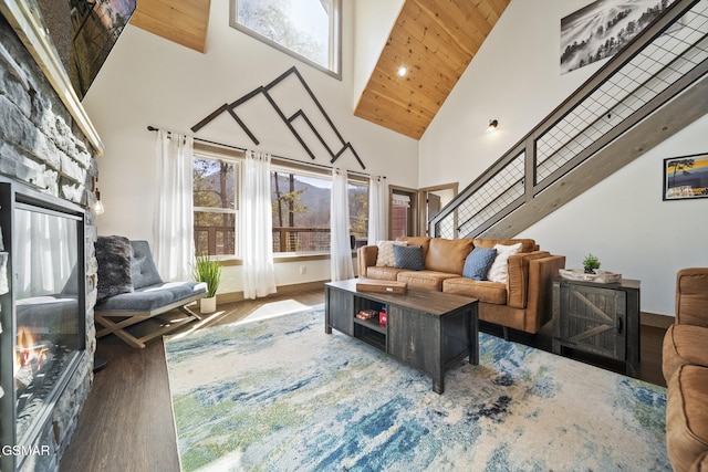 living area featuring stairway, wood finished floors, baseboards, a high ceiling, and a fireplace