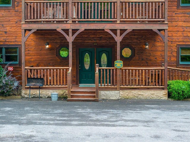 doorway to property with a balcony and covered porch