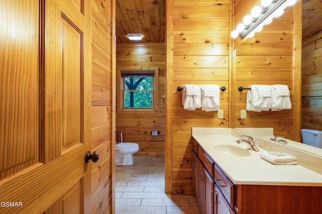 bathroom featuring vanity, toilet, and wood walls