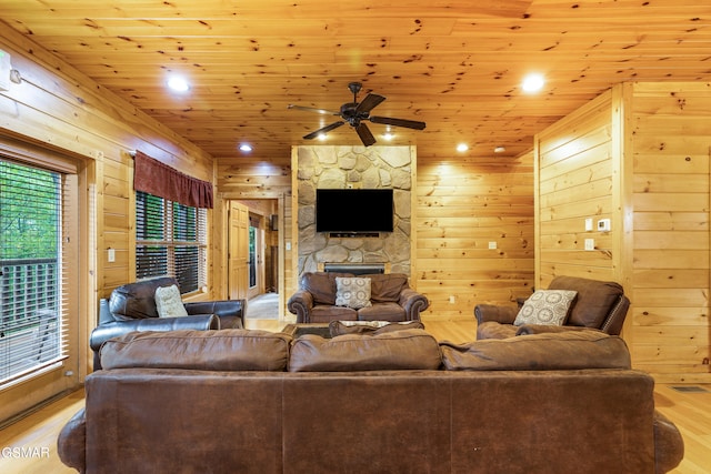 living room with wooden ceiling, wooden walls, light hardwood / wood-style flooring, ceiling fan, and a fireplace