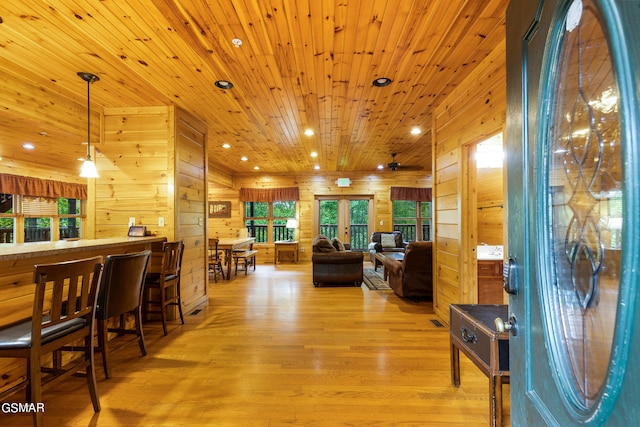 interior space with french doors, wooden walls, ceiling fan, light hardwood / wood-style floors, and wood ceiling