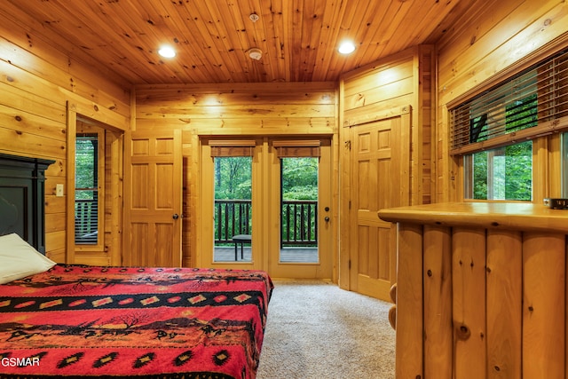 bedroom with wood walls, access to exterior, and carpet floors