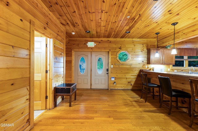 entryway with sink, light wood-type flooring, wood walls, and wood ceiling