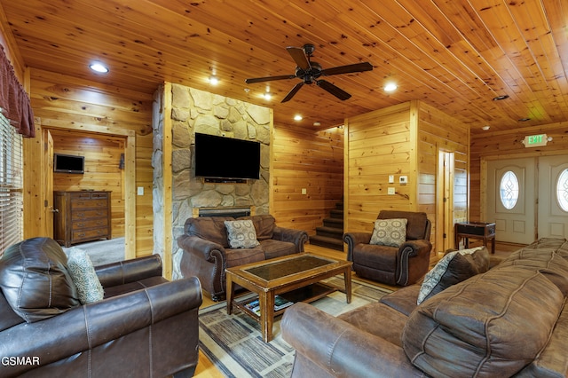 living room with a fireplace, wooden walls, ceiling fan, and wooden ceiling