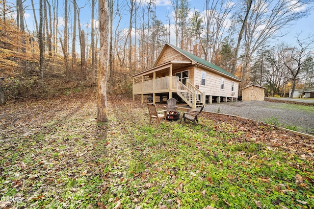3176 Mcgill Rd, Sevierville, TN 37862 - view of front of house with a wooden deck, gravel driveway, an outdoor fire pit, a storage unit, and an outbuilding