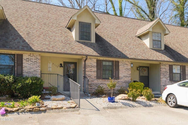 view of front of house featuring brick siding and roof with shingles