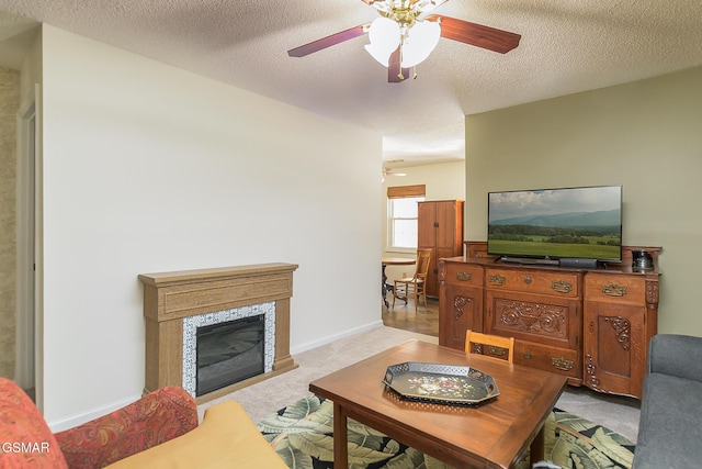 carpeted living room with a tiled fireplace, ceiling fan, and a textured ceiling