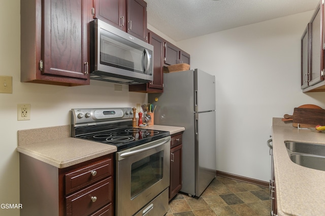 kitchen with light countertops, appliances with stainless steel finishes, baseboards, and a textured ceiling