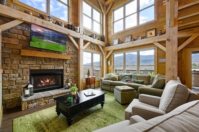 living room featuring a high ceiling, a fireplace, wood walls, and wood-type flooring