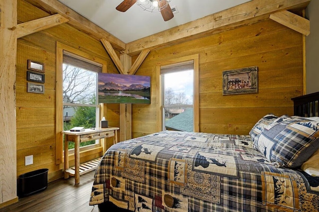 bedroom with ceiling fan, wooden walls, and multiple windows