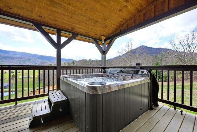 wooden deck with a hot tub and a mountain view