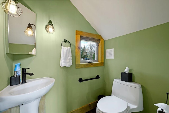 bathroom with toilet, vaulted ceiling, and sink