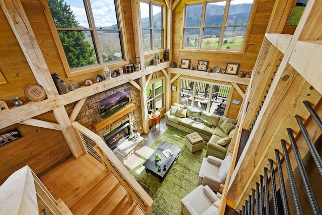 living room featuring wood-type flooring, wooden walls, and a stone fireplace