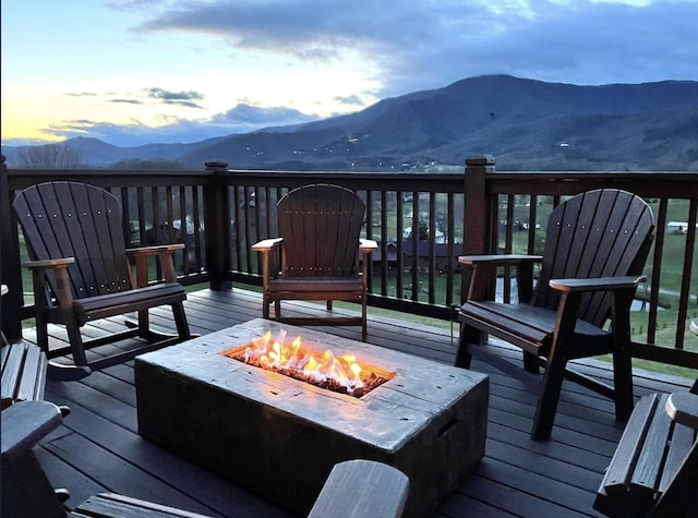 deck at dusk with an outdoor fire pit and a mountain view