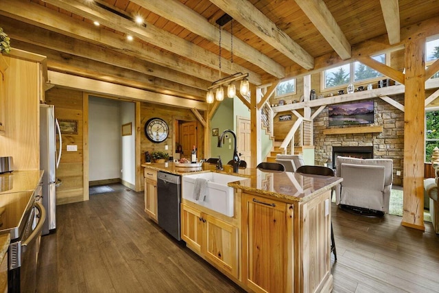 kitchen with wooden ceiling, a kitchen island with sink, stainless steel appliances, beamed ceiling, and light stone countertops