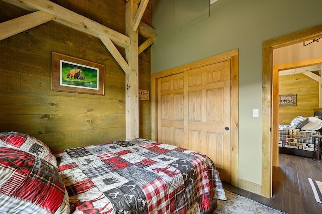 bedroom featuring a closet, wood walls, and dark hardwood / wood-style floors