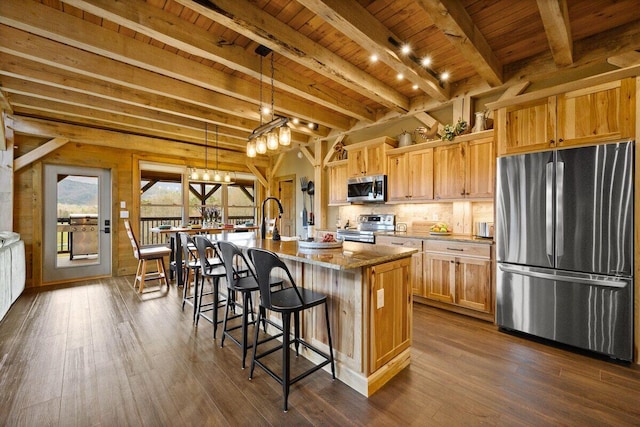 kitchen with wooden ceiling, a kitchen island with sink, stainless steel appliances, beam ceiling, and decorative light fixtures