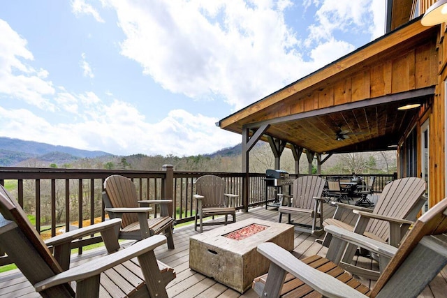 deck featuring a mountain view, ceiling fan, and a fire pit