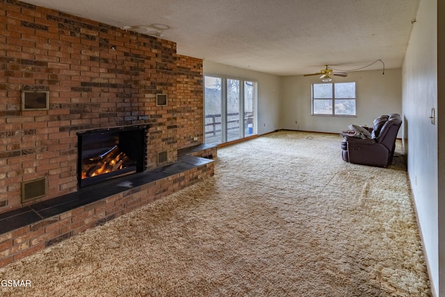 carpeted living room with ceiling fan, a fireplace, and a textured ceiling