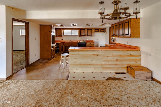 kitchen featuring pendant lighting, sink, a breakfast bar, black dishwasher, and kitchen peninsula