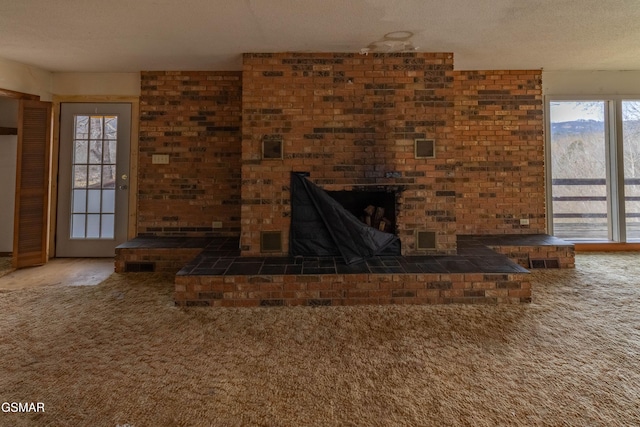 unfurnished living room featuring a fireplace, carpet floors, and a textured ceiling