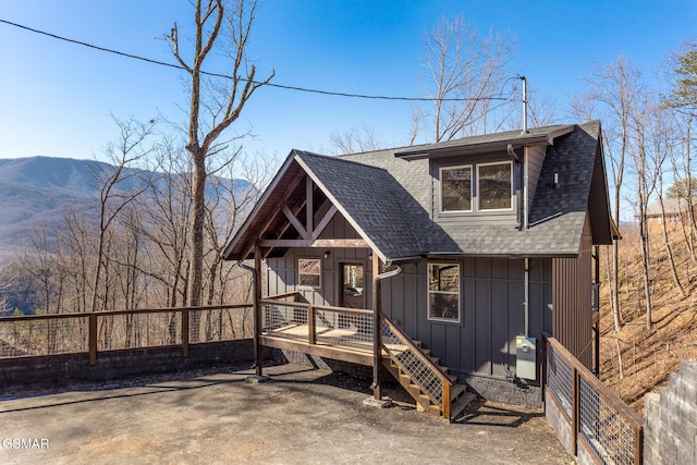 rustic home with a mountain view, board and batten siding, a shingled roof, and fence