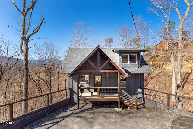 view of front facade featuring fence, board and batten siding, and roof with shingles