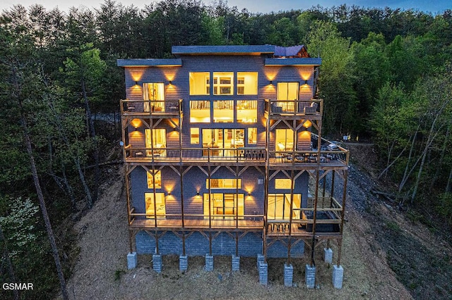 back of property with a balcony and a wooded view