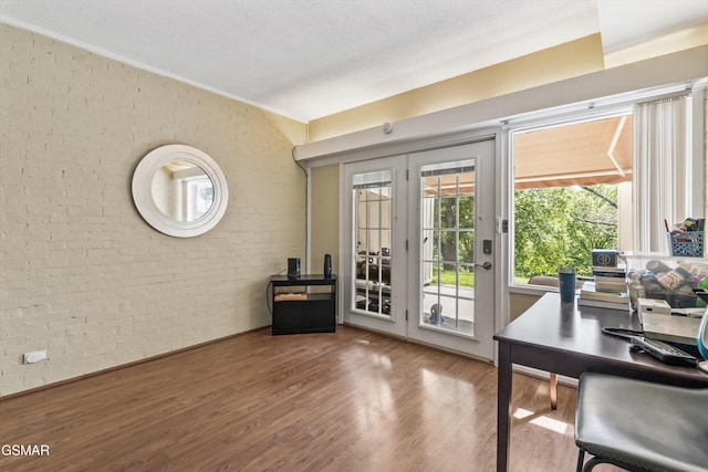 home office with brick wall and wood finished floors