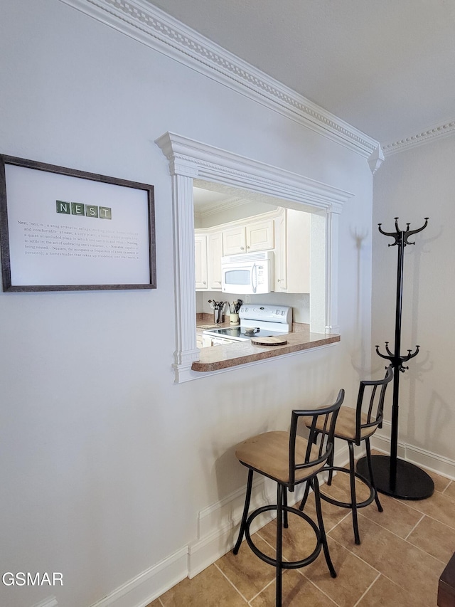 kitchen featuring white cabinetry, crown molding, light tile patterned flooring, and white appliances