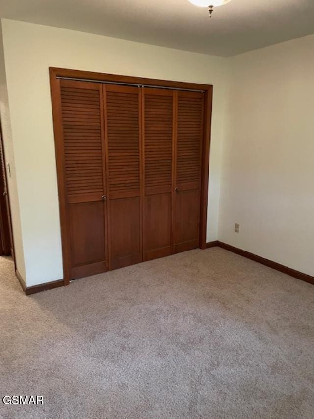 unfurnished bedroom featuring a closet and light colored carpet