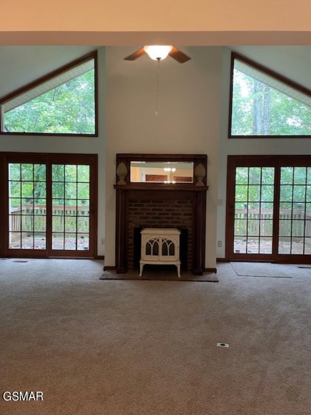 unfurnished living room featuring carpet, ceiling fan, a towering ceiling, and a fireplace