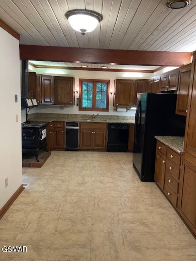 kitchen with light stone countertops, beamed ceiling, and black appliances