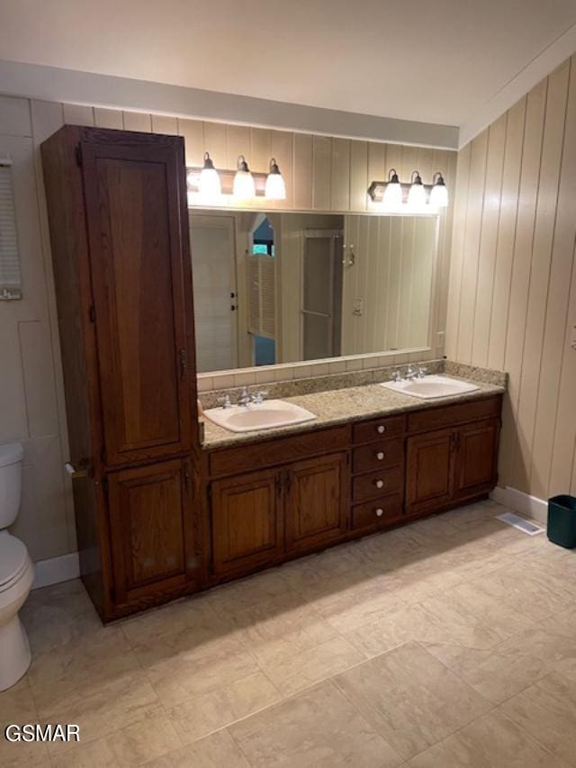 bathroom with vanity, toilet, and wooden walls