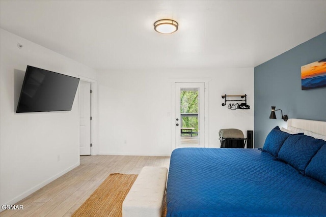 bedroom with light wood-style floors, baseboards, and access to outside