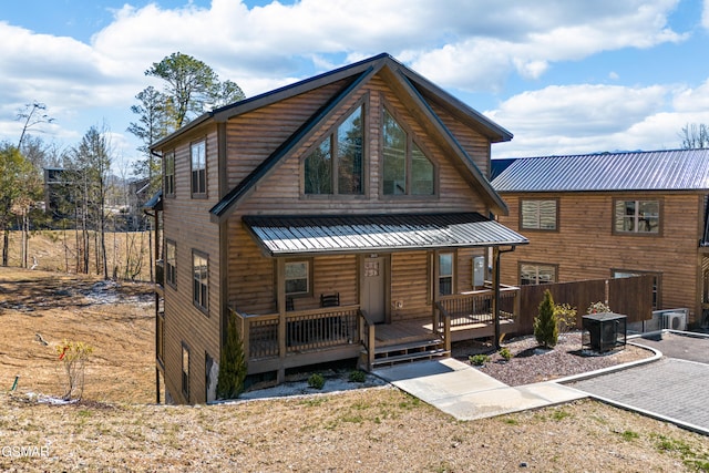 view of front of property with covered porch, faux log siding, metal roof, and a standing seam roof