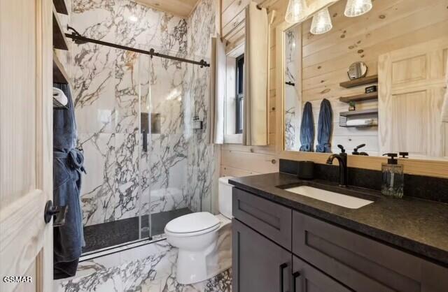 bathroom featuring wood walls, vanity, walk in shower, and toilet