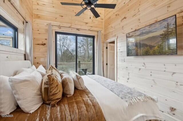 bedroom with ceiling fan, wooden walls, and access to outside