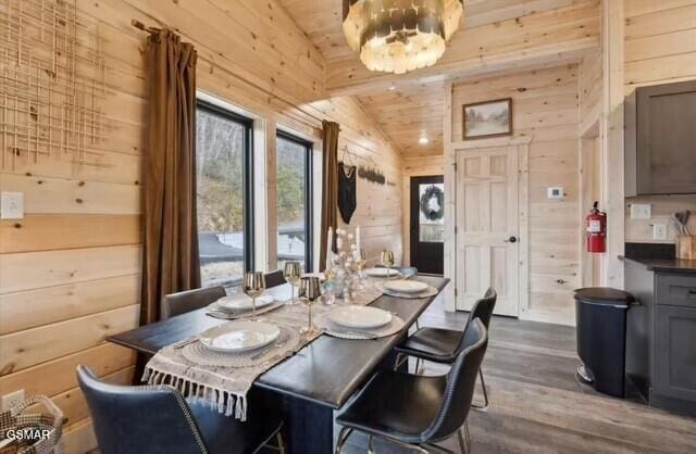 dining room featuring lofted ceiling, wood walls, an inviting chandelier, wooden ceiling, and hardwood / wood-style floors