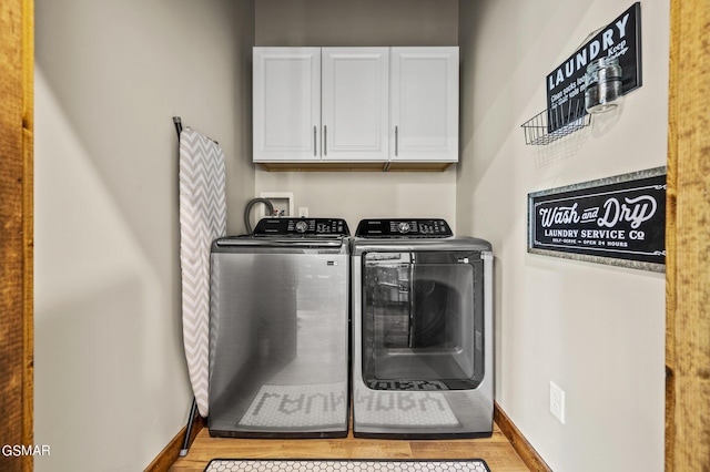 laundry area with washing machine and dryer, cabinets, and light hardwood / wood-style floors