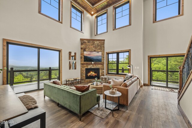 living room with hardwood / wood-style floors, wooden ceiling, a fireplace, and a towering ceiling