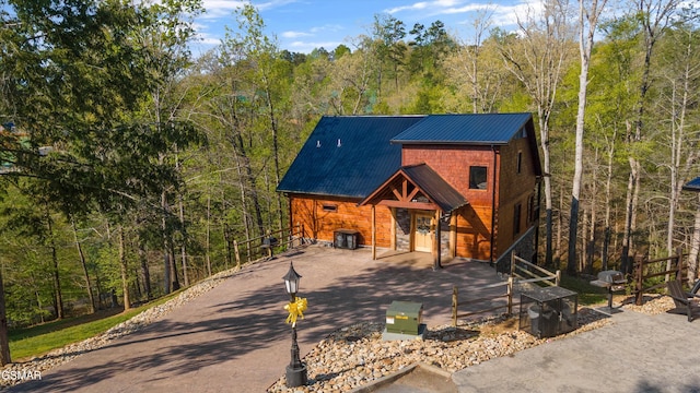 view of front of house featuring a forest view and metal roof
