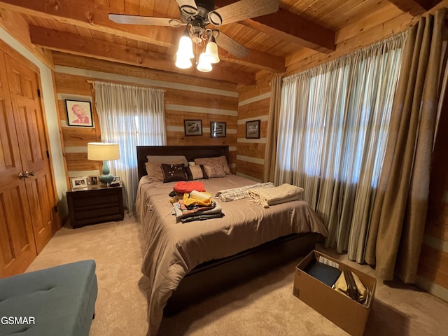 bedroom featuring wooden walls, ceiling fan, beam ceiling, wooden ceiling, and light colored carpet