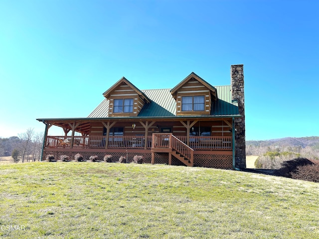 back of house with metal roof, a chimney, a standing seam roof, covered porch, and a yard