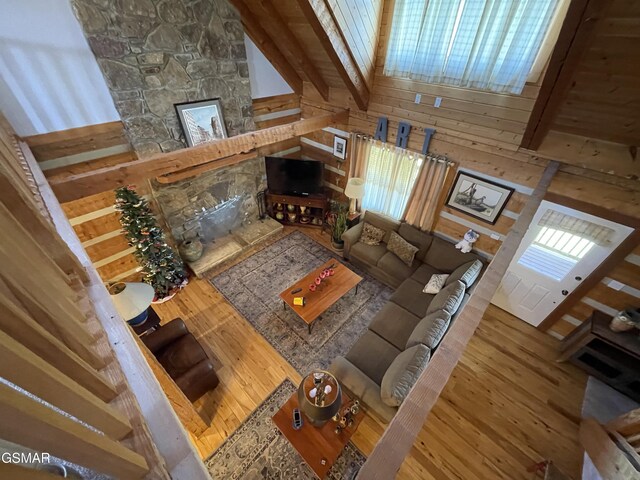 living area with beamed ceiling, high vaulted ceiling, wood finished floors, and wooden walls
