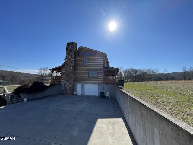 view of home's exterior featuring concrete driveway, a garage, and a chimney