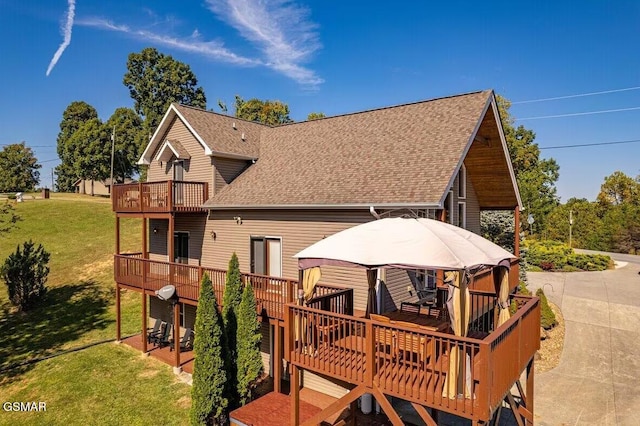 back of house with a gazebo, a balcony, a deck, and a lawn